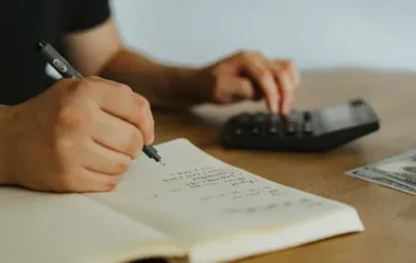 노트와 계산기로 비용을 정리하는 손